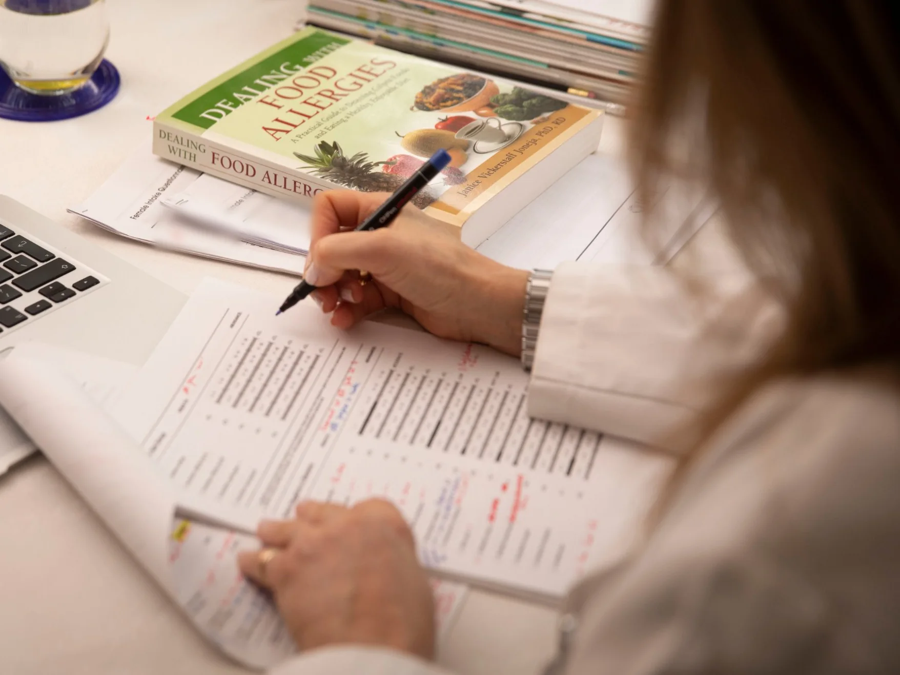 Nutritional therapist annotating a client’s food sensitivity test results alongside their intake questionnaire